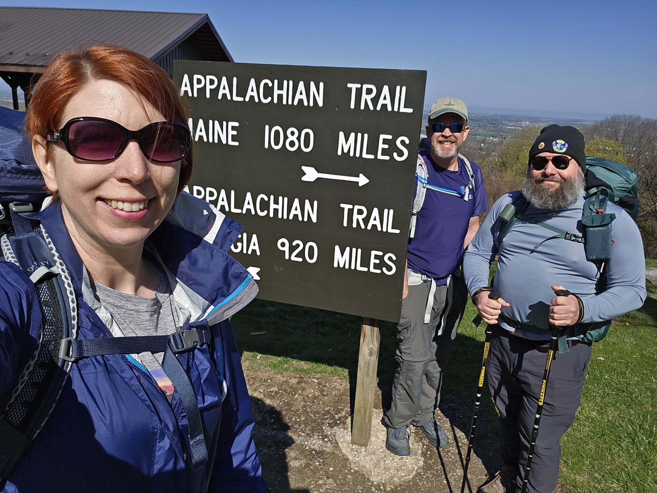 Three smiling hikers in front of an Appalachian trail sign